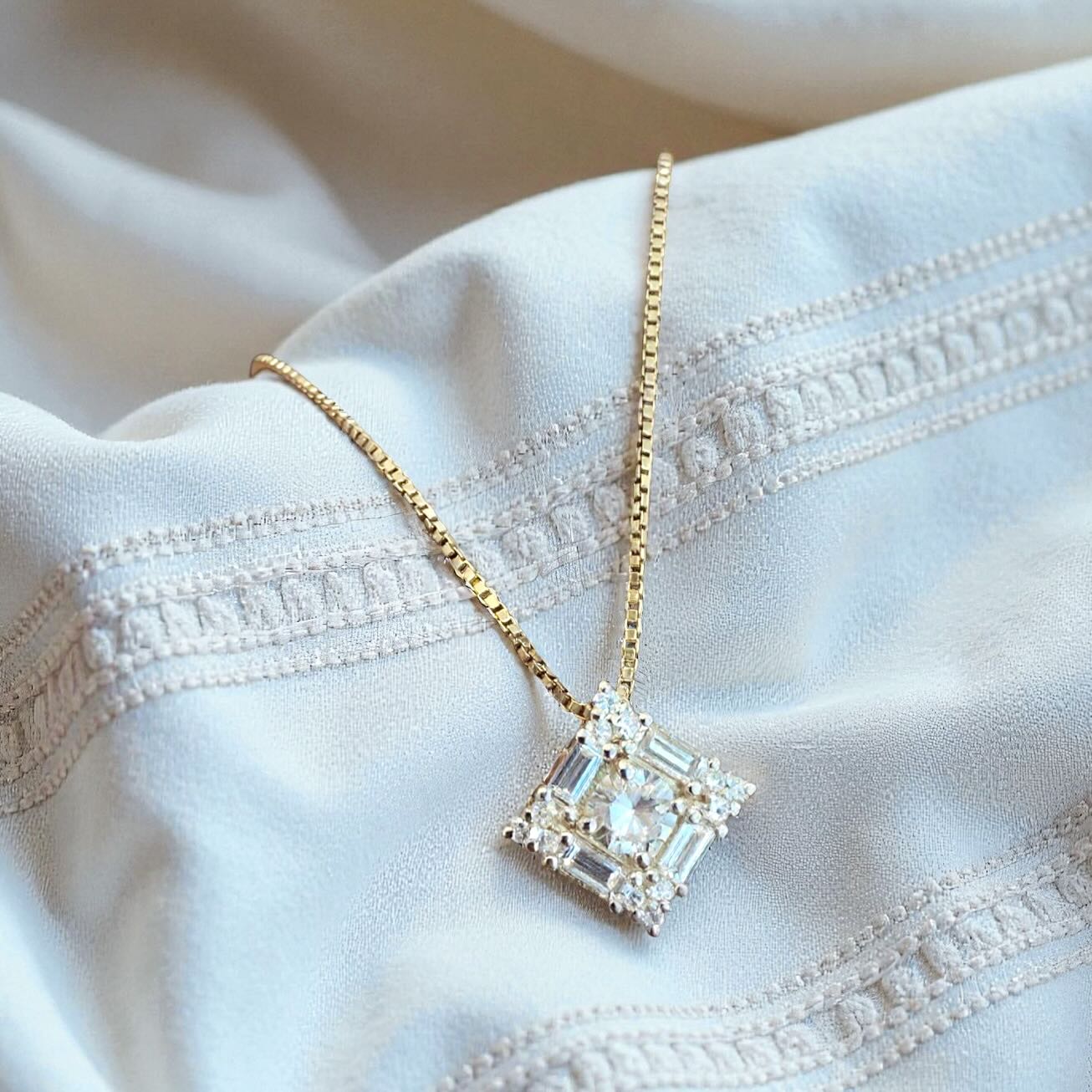 Gold necklace with a diamond pendant on a white fabric background