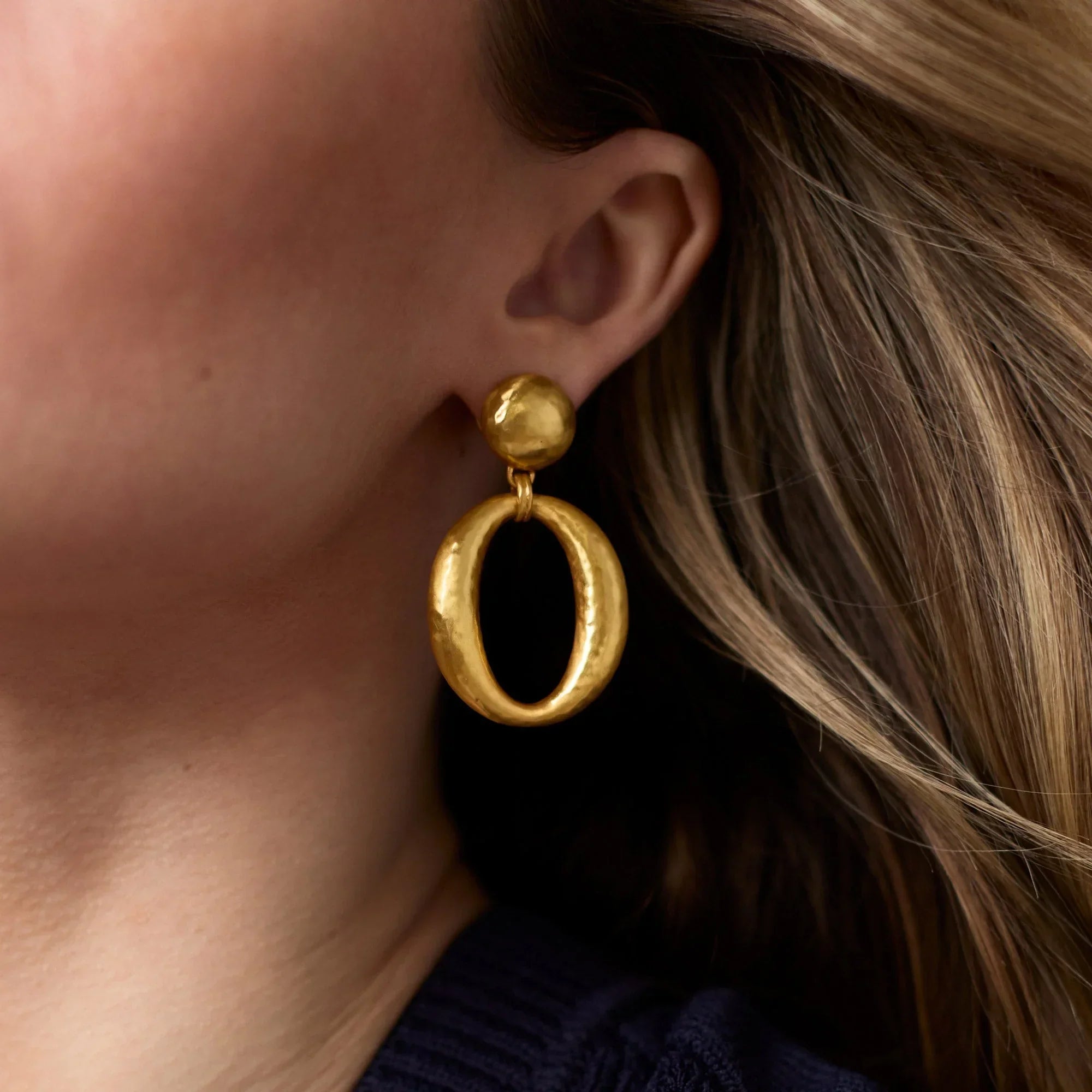 Gold hoop earrings worn by a person with blonde hair.