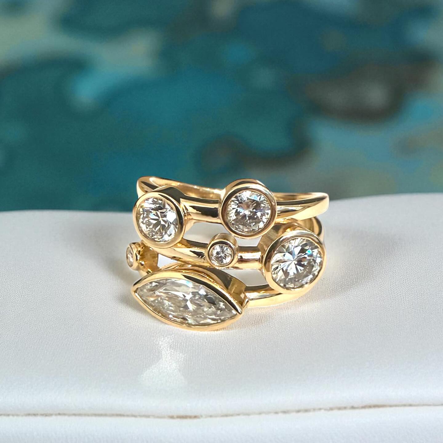 gold and diamond bridge ring on a white and teal background