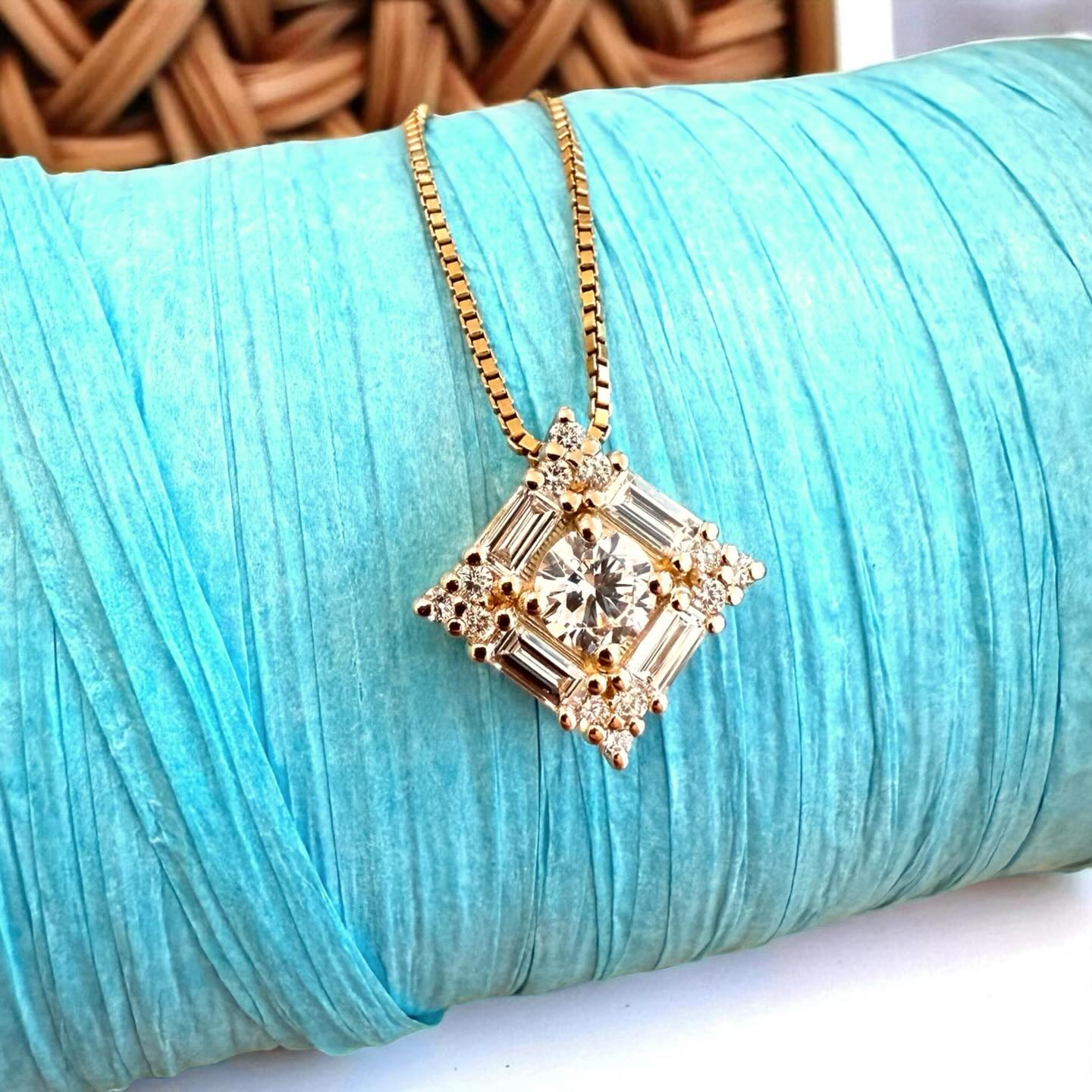 Gold necklace with a diamond pendant on a turquoise fabric background