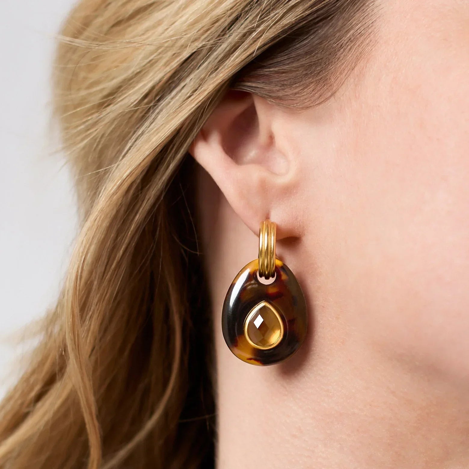 Close-up of a tortoiseshell hoop earring worn by a person with blonde hair.