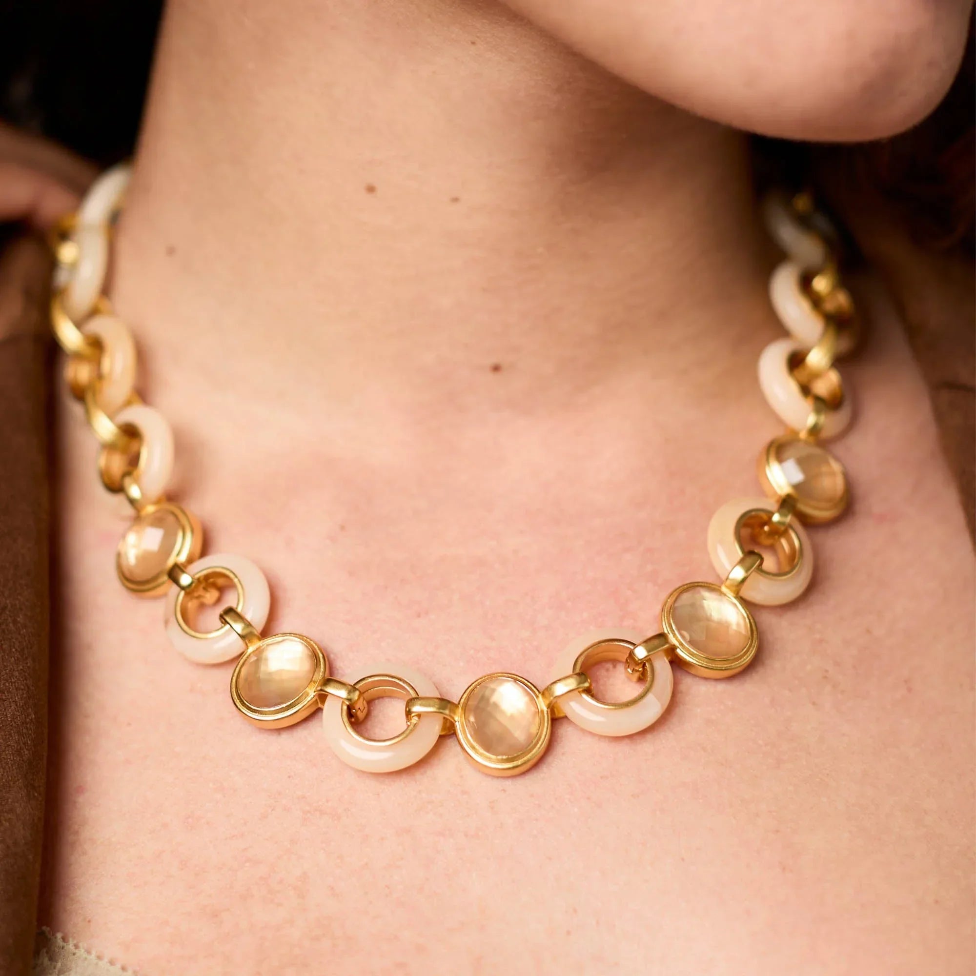 Gold and beige necklace on a person's neck