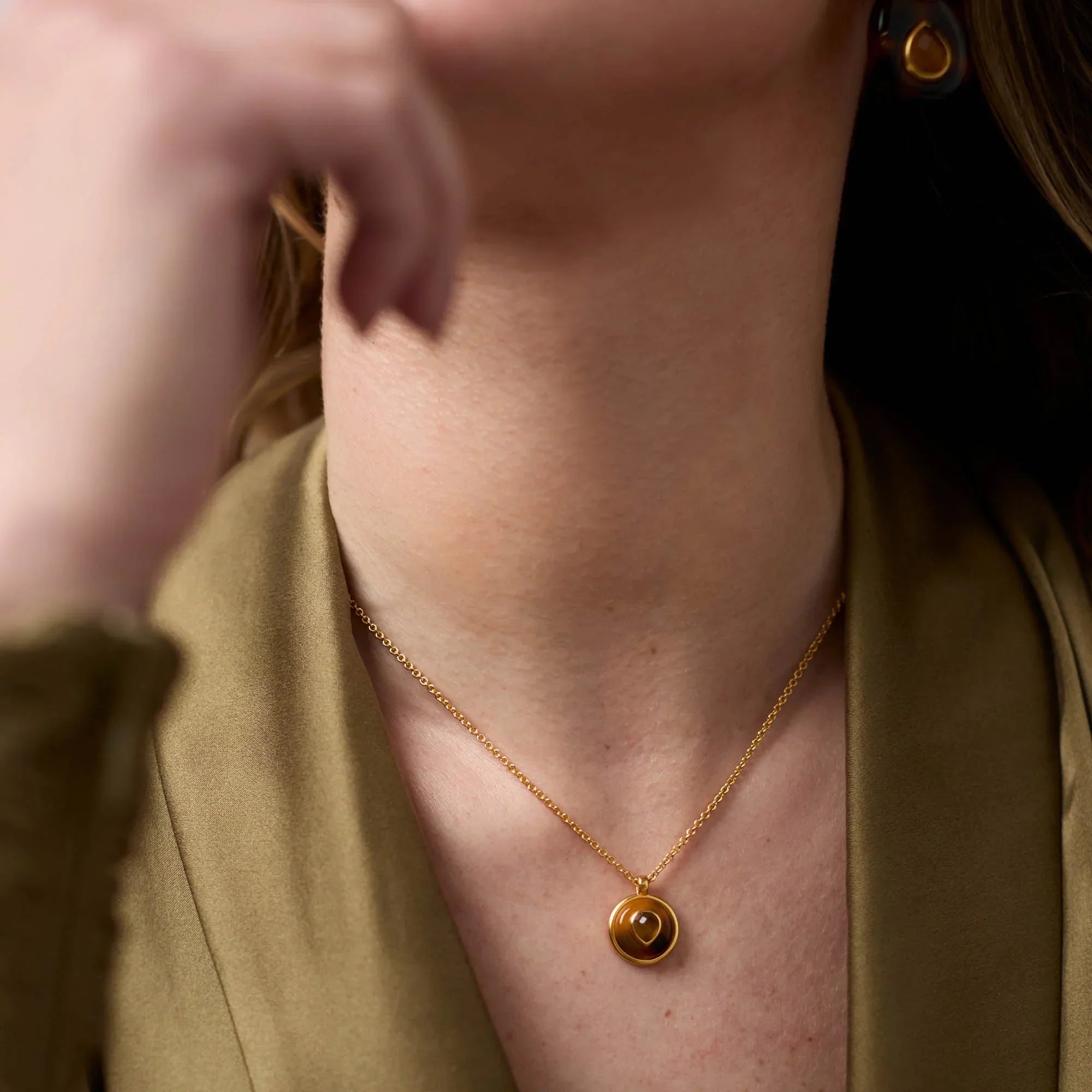 Person wearing a gold necklace with a pendant