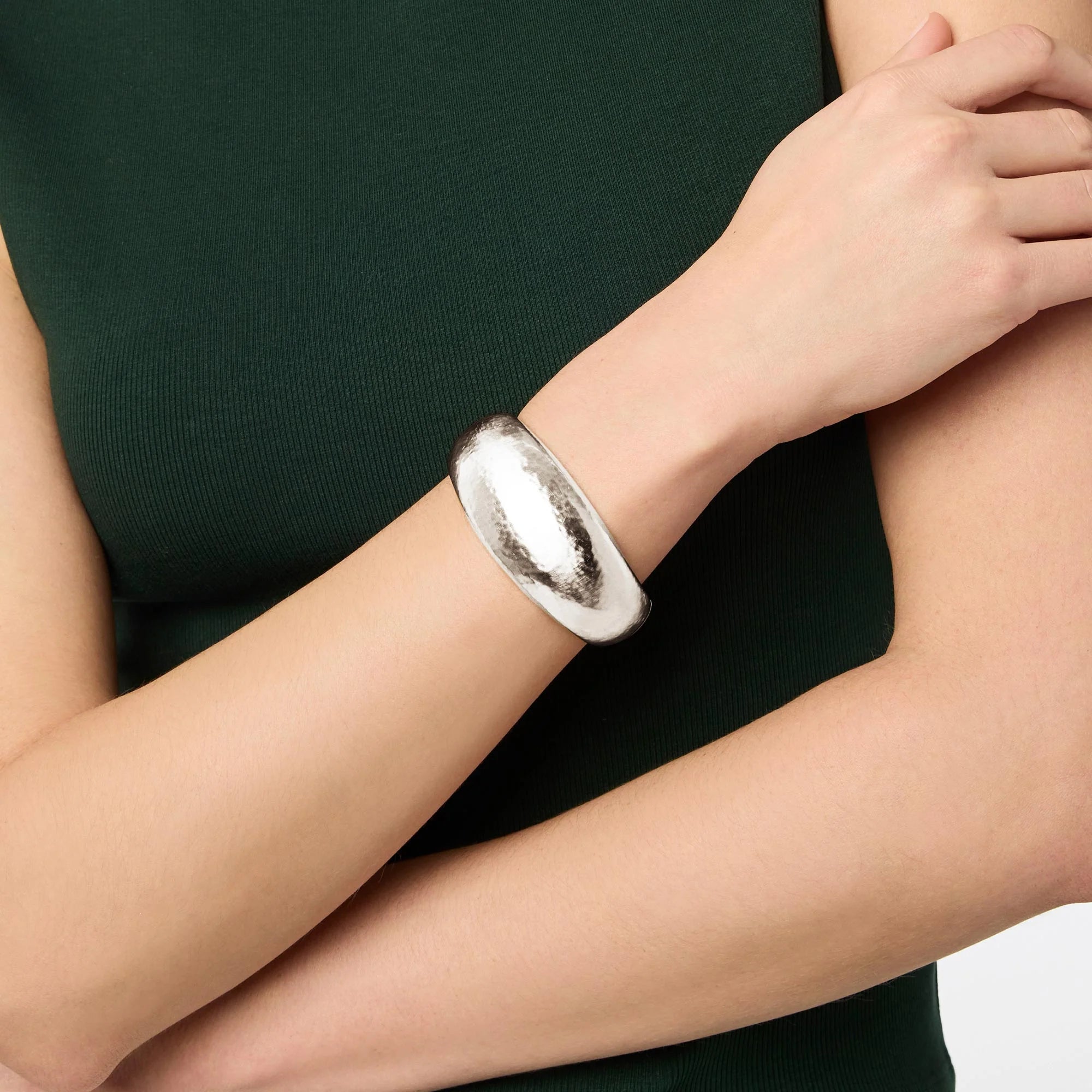 Silver bracelet on a person's wrist with a plain background