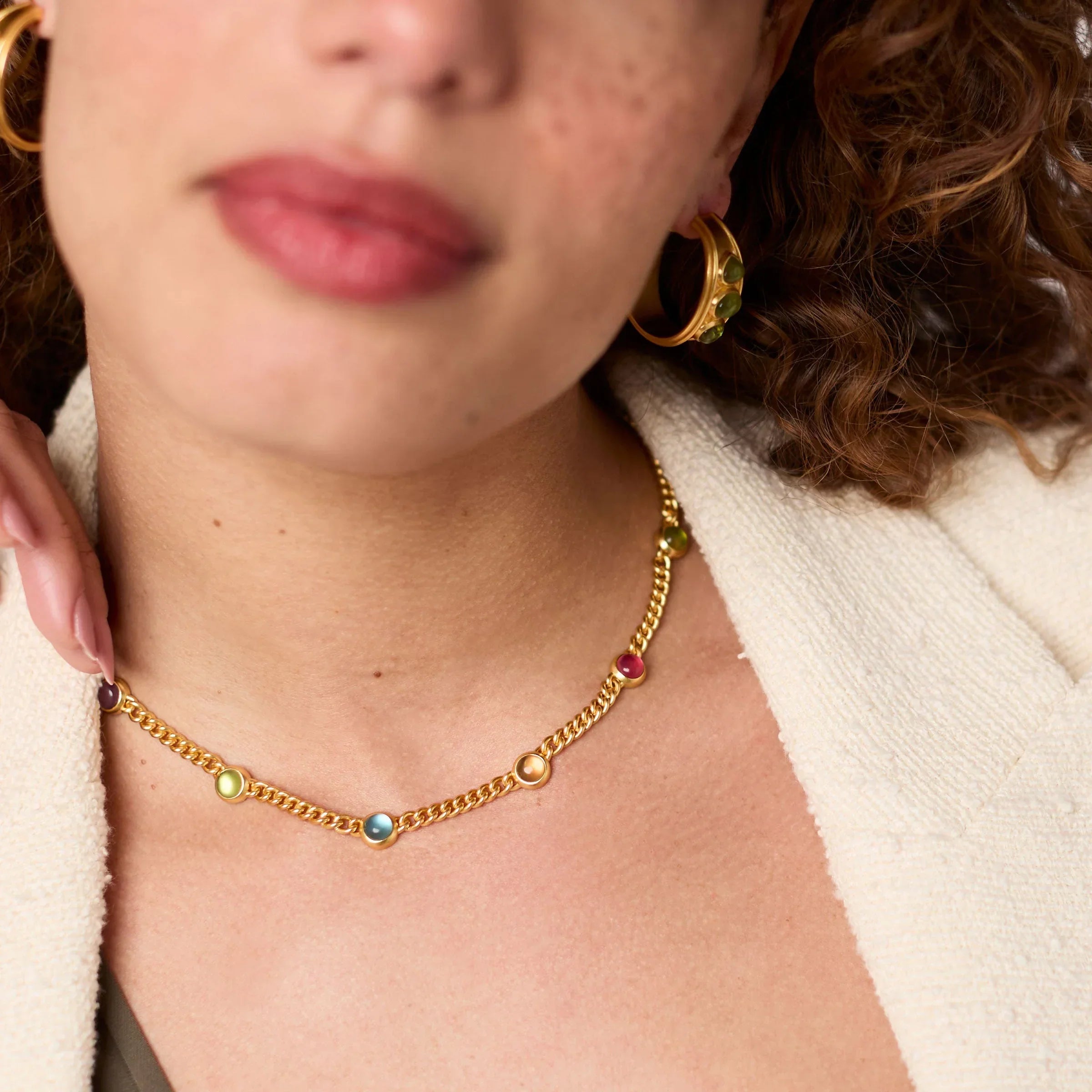 Close-up of a person wearing a gold chain necklace with colorful beads.