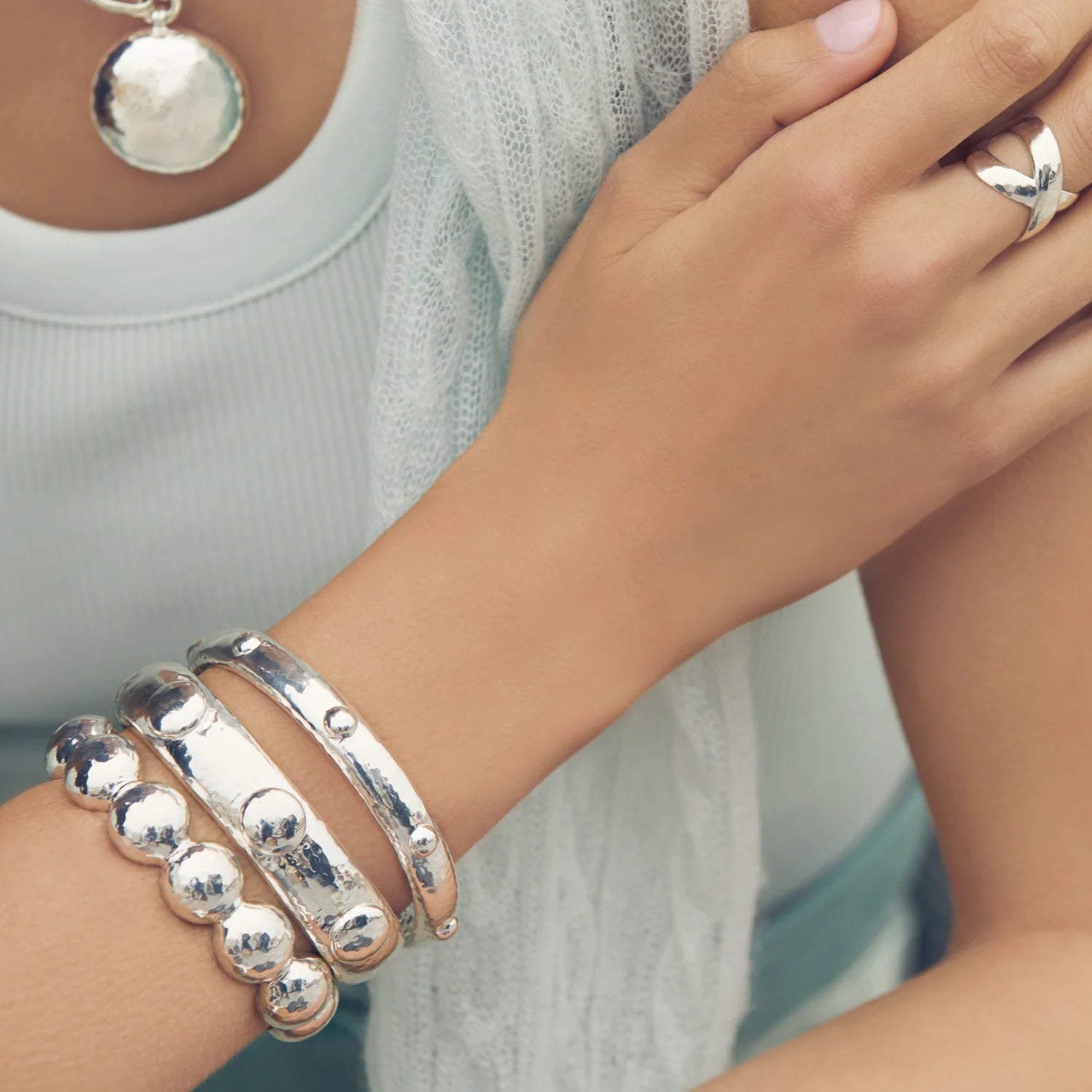 Silver bracelets on a person's wrist and hand
