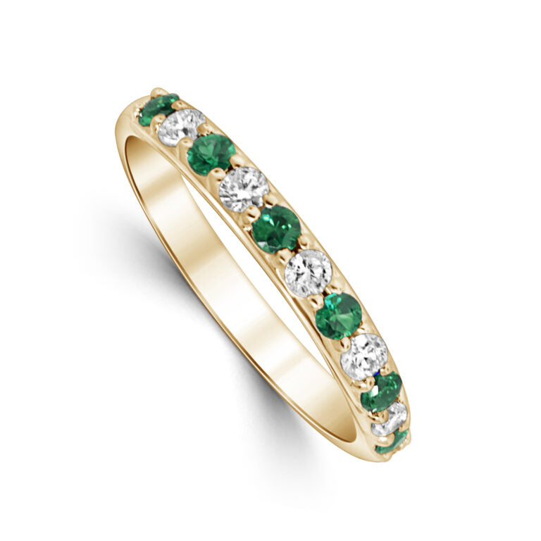 Gold ring with emeralds and diamonds on a white background
