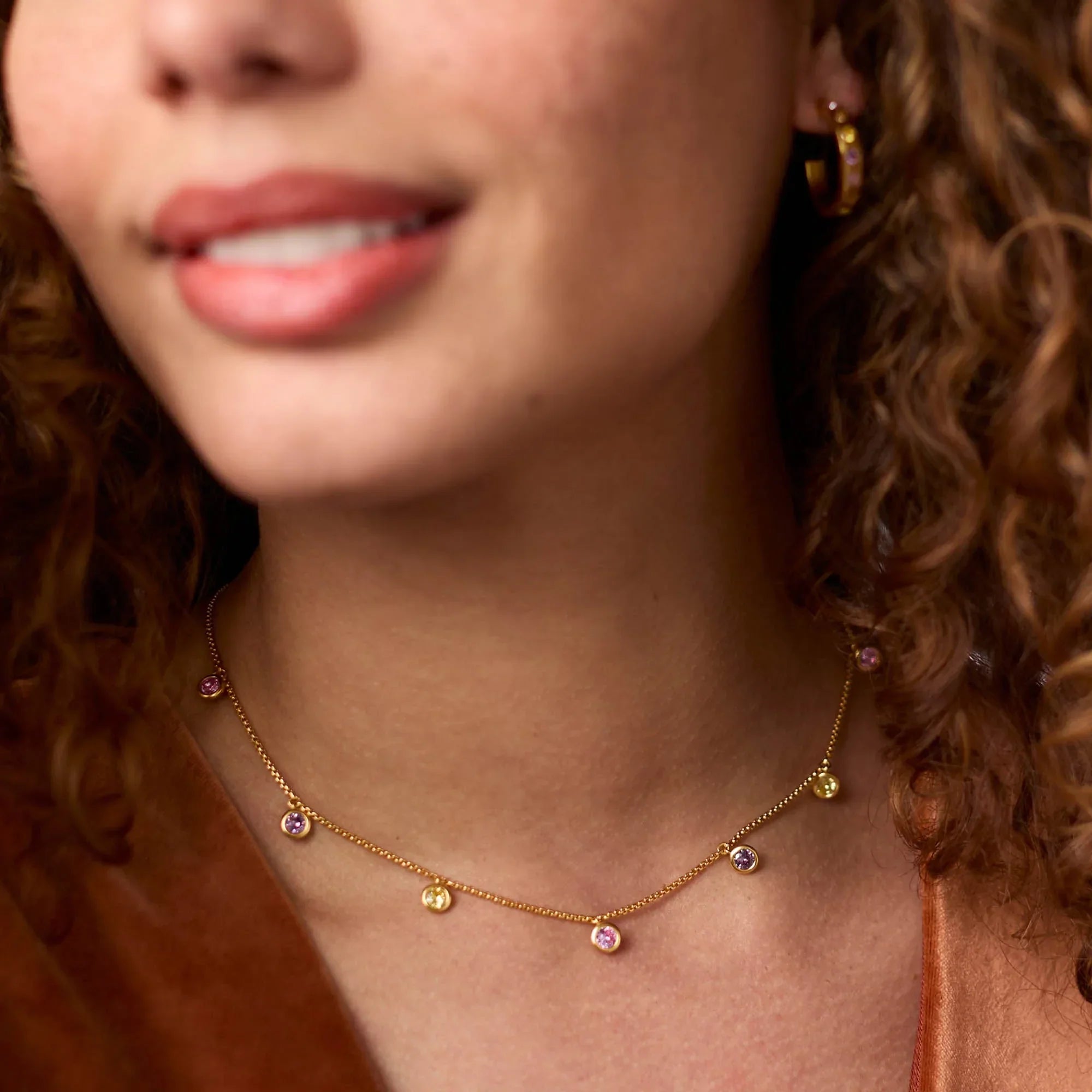 Close-up of a woman wearing a gold necklace with colorful beads.
