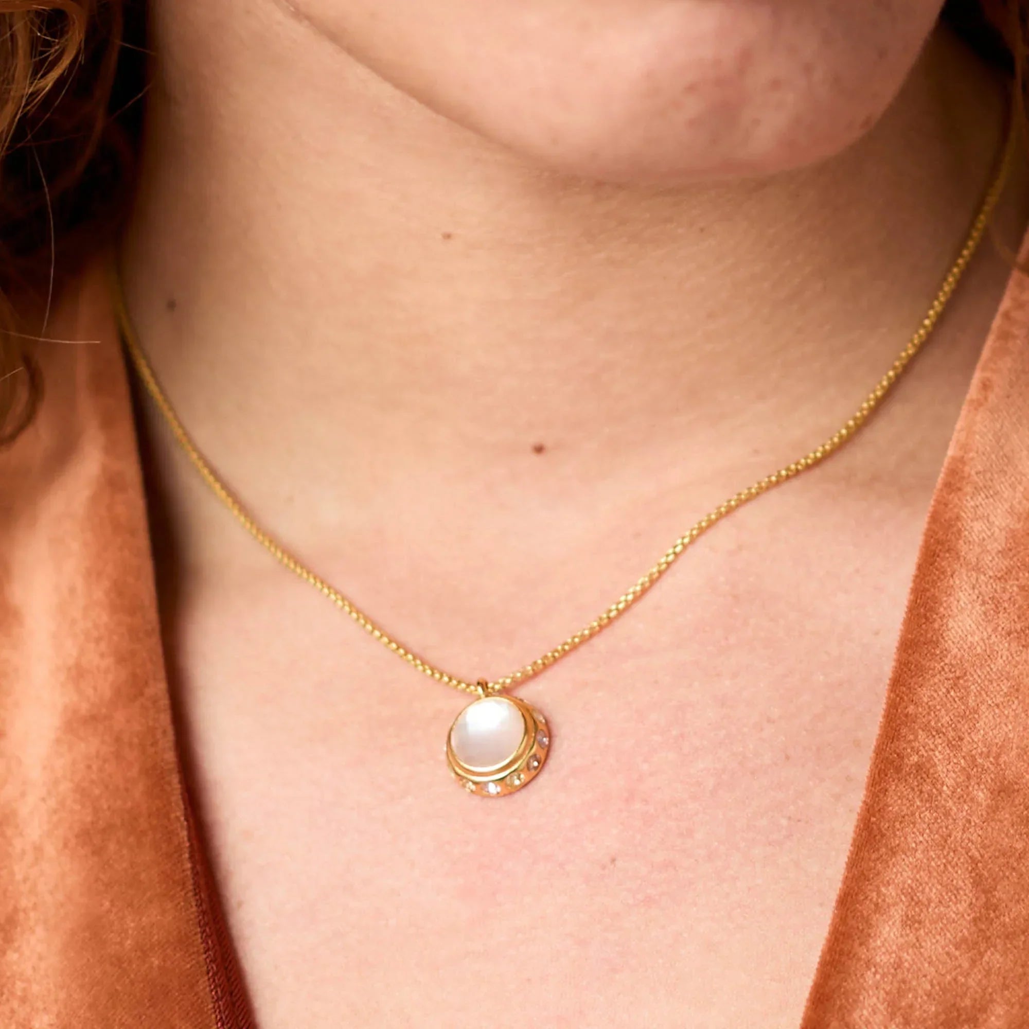 Gold necklace with a pendant worn by a person