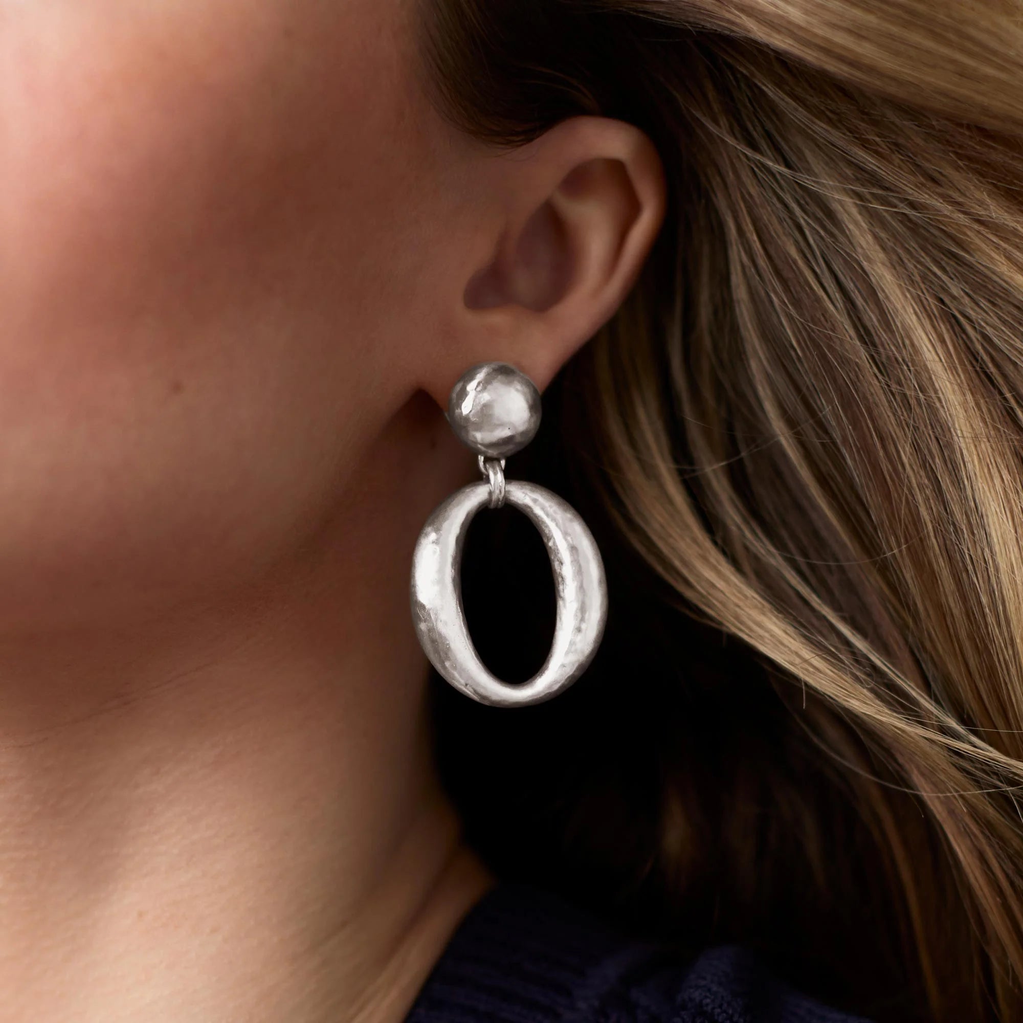 Silver hoop earrings worn by a person with brown hair.