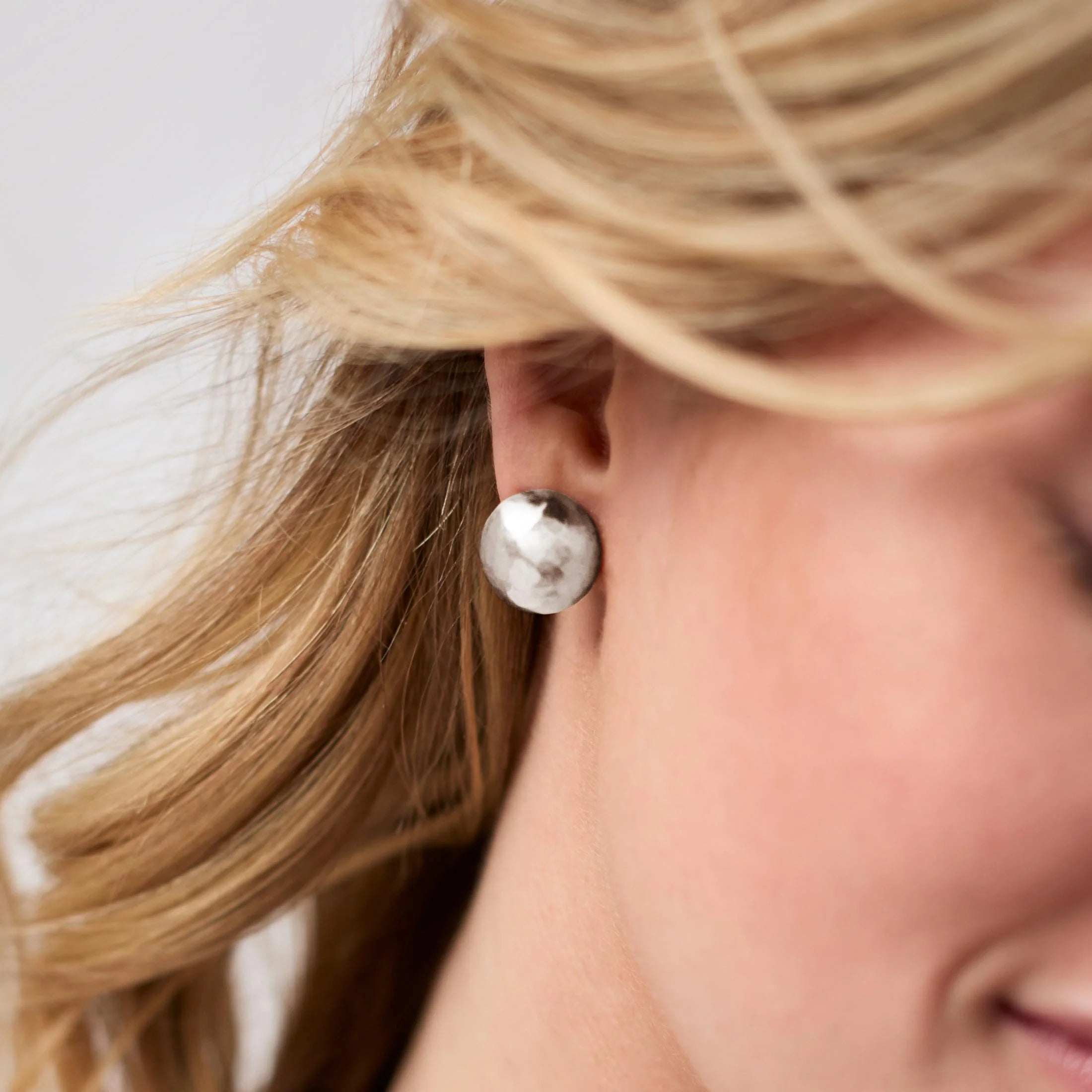 Close-up of a person wearing pearl earrings with a neutral background