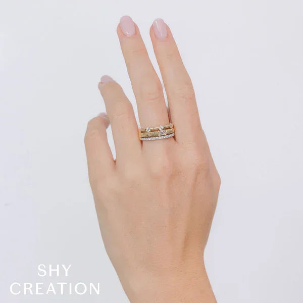 Hand wearing a ring with 'SHY CREATION' branding on a light background