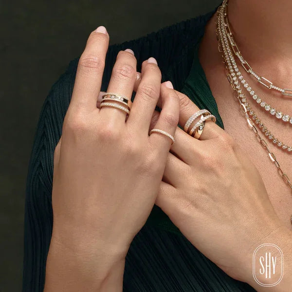 Close-up of hands wearing multiple rings and a necklace on a dark background