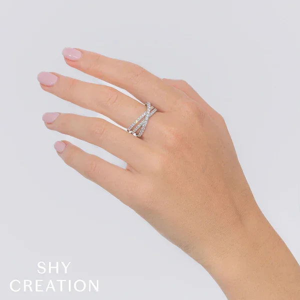 Hand wearing a silver ring with small diamonds on a light gray background, branded 'SHY CREATION'.
