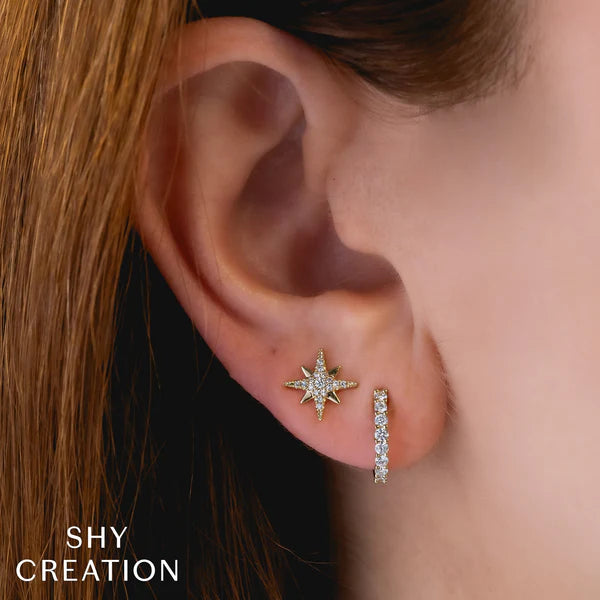Star-shaped earrings worn by a person with 'SHY CREATION' branding.