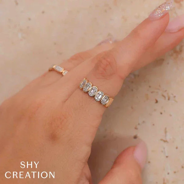 Gold ring with diamonds on a finger against a neutral background, with 'SHY CREATION' branding.