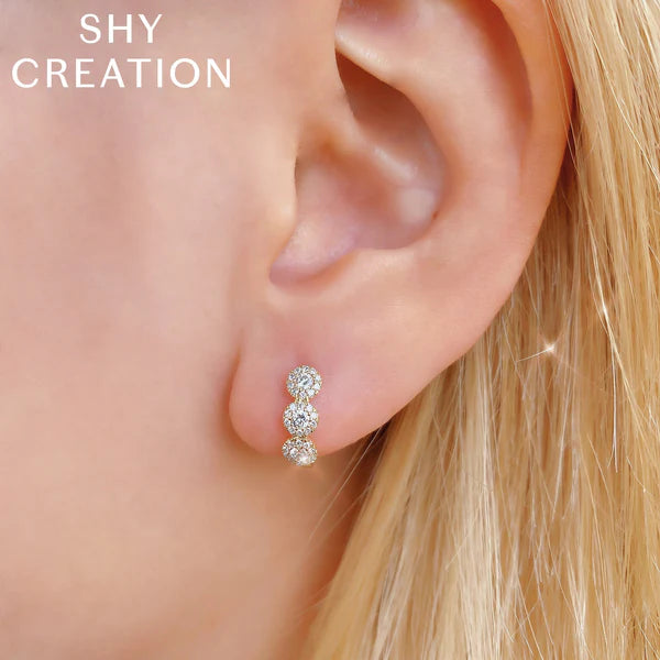 Close-up of an ear wearing a diamond earring with 'SHY CREATION' branding.